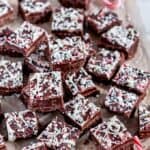 Holiday Chocolate Peppermint Fudge with holiday sprinkles and crushed candy canes on parchment