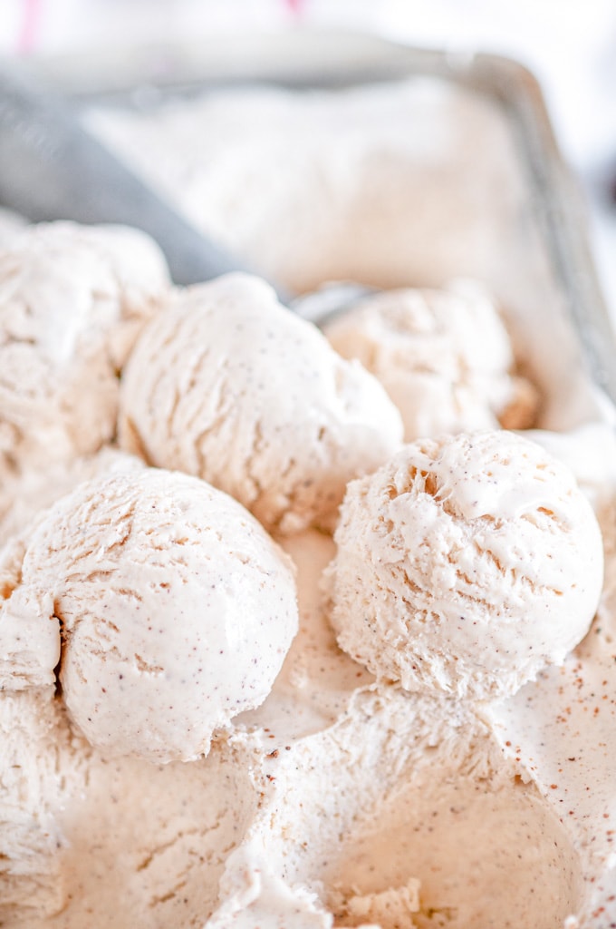 No Churn Egg Nog Ice Cream scooped into balls with gray scoop in bread pan