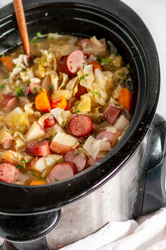 Slow Cooker Kielbasa Cabbage Stew in crock pot with wooden spoon