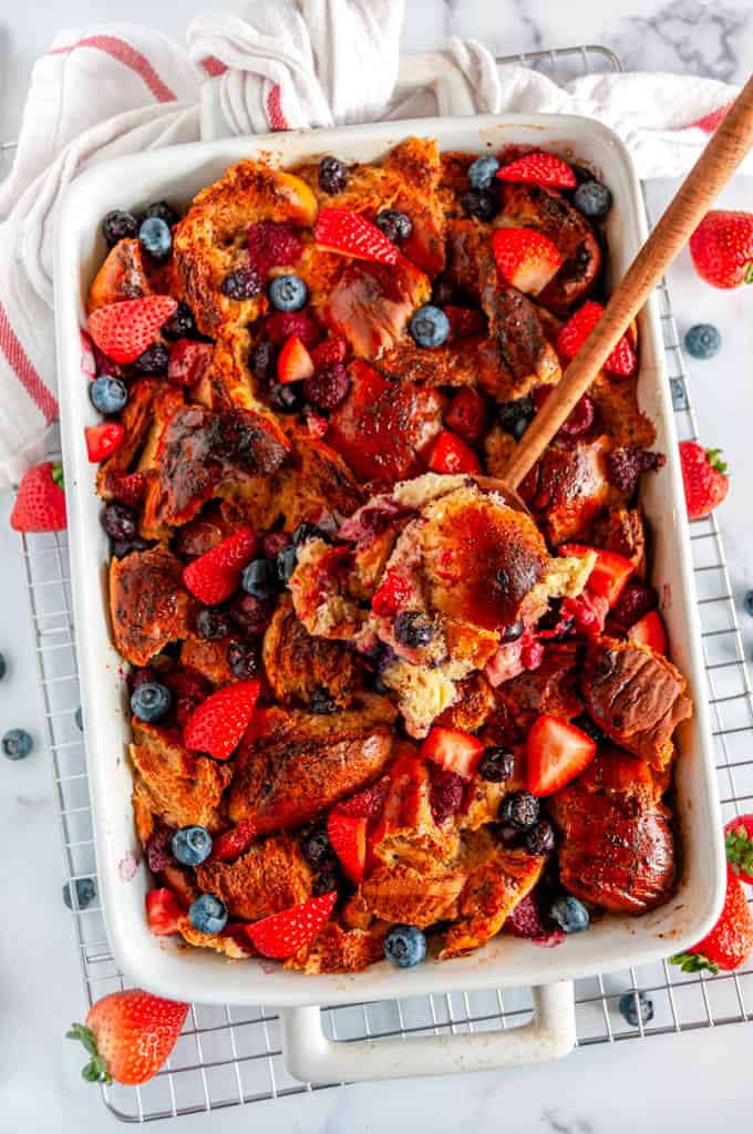 Baked Overnight Berry French Toast in white casserole dish with wooden spoon on wire rack