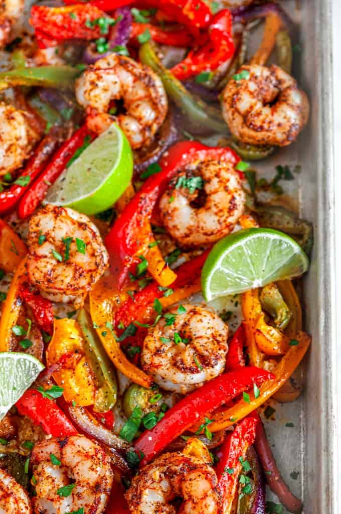 Sheet Pan Shrimp Fajitas with limes and bell peppers on baking pan close up