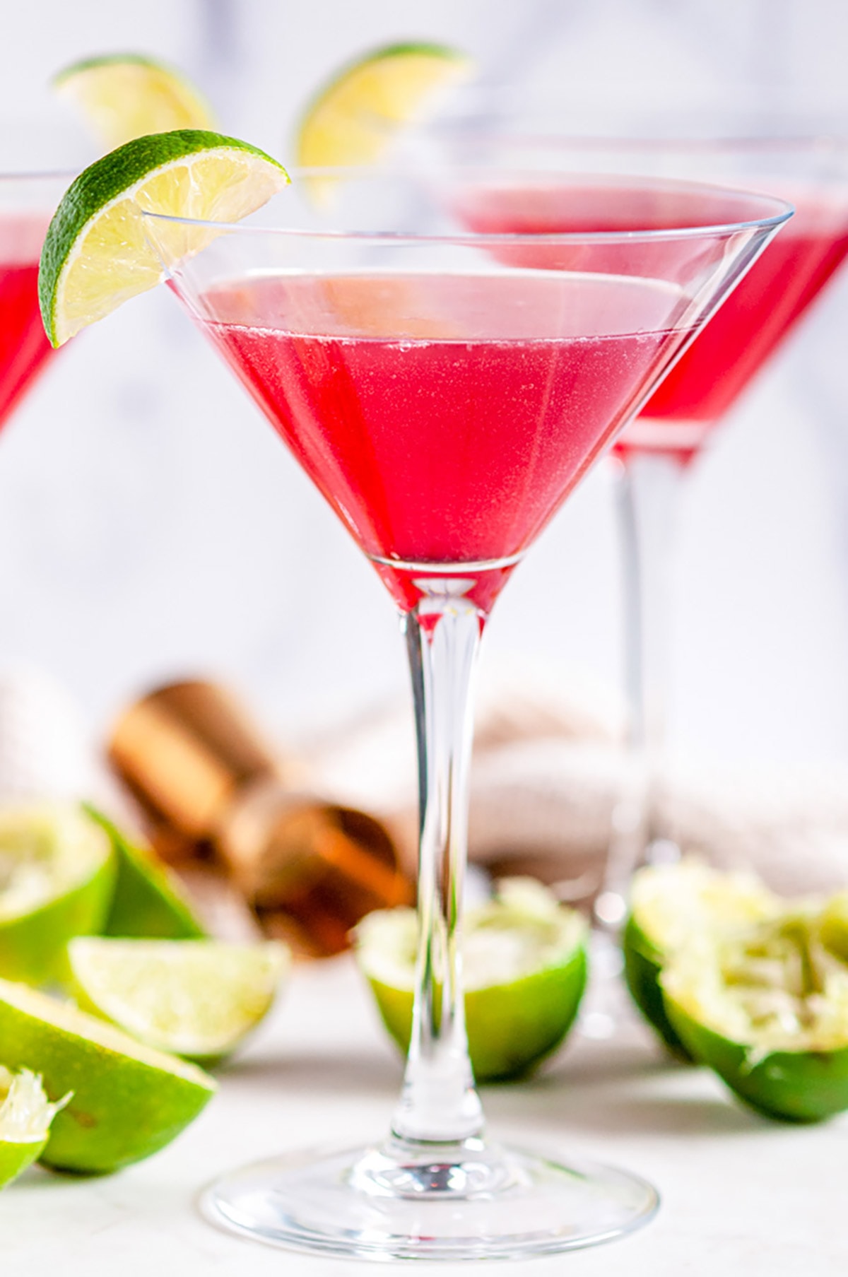 Classic Cosmopolitan Cocktail in martini glasses with lime wedge on white marble