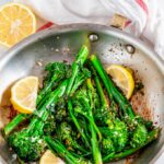 Quick and Easy Lemon Garlic Broccolini in skillet with lemon wedges and tea towel
