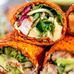 Healthy Chicken Avocado Wraps with kale salad mix on white plate and marble