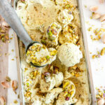 No Churn Pistachio Ice Cream in metal bread pan with ice cream scoop on white marble