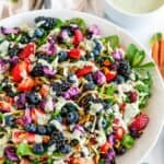 Superfood Berry Salad with Creamy Lemon Herb Dressing in white bowl on marble with copper dinnerware