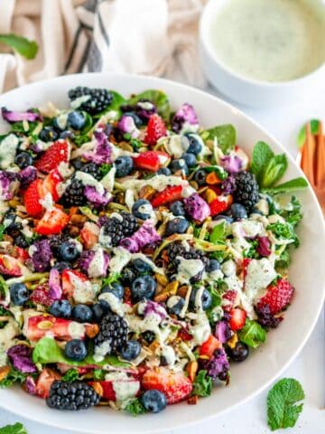 Superfood Berry Salad with Creamy Lemon Herb Dressing in white bowl on marble with copper dinnerware