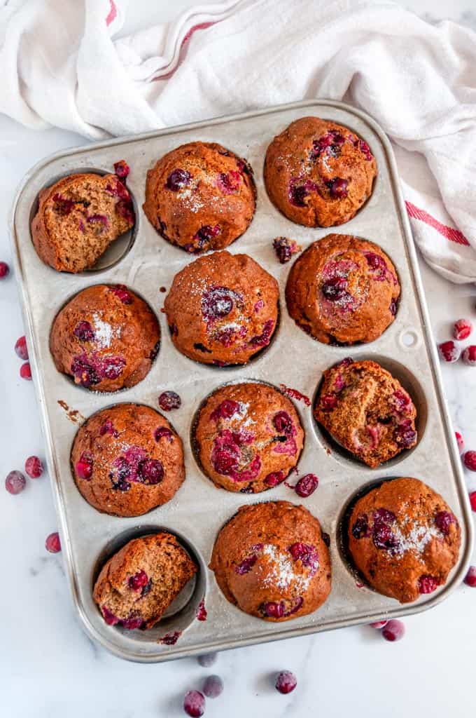 Easy Autumn Chai Spice Cranberry Muffins in muffin tin with tea towel on white marble