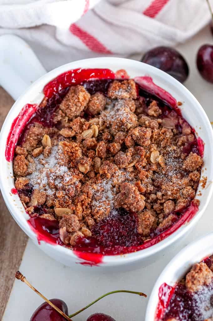 End of Summer Cherry Crumble in white ramekins on white marble