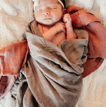 Newborn baby swaddled in red and gray blankets