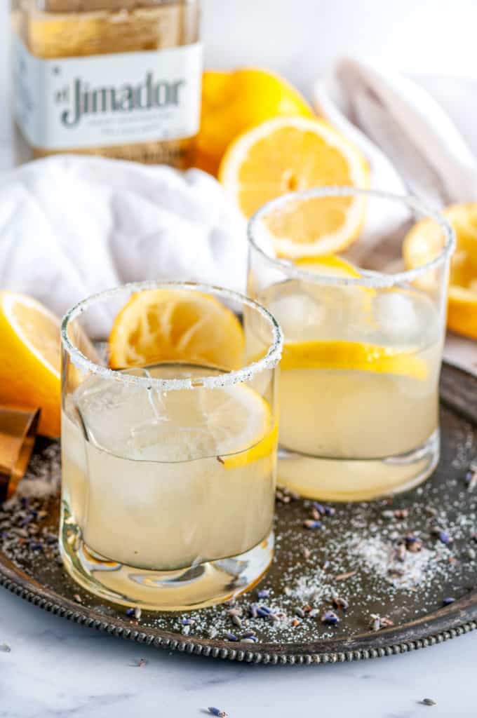 Lemon Lavender Margaritas in cocktail glasses with ice on gray plate