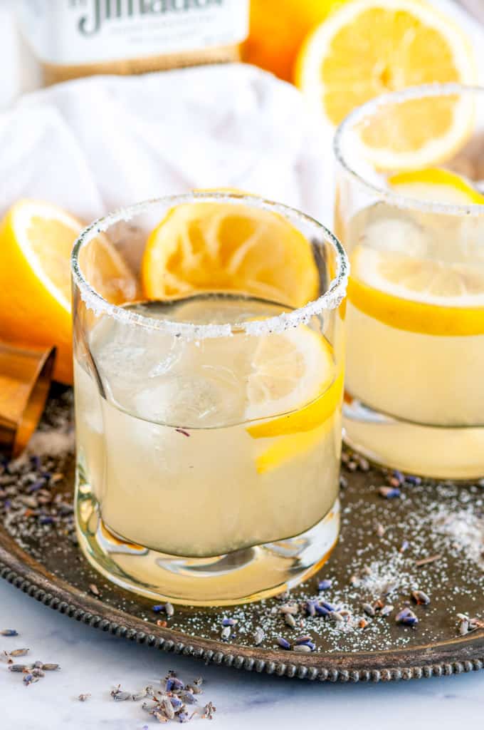Lemon Lavender Margaritas in cocktail glasses with ice on gray plate