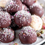 Dark Chocolate Rose Truffles sprinkled with rose buds and sanding sugars on white plate