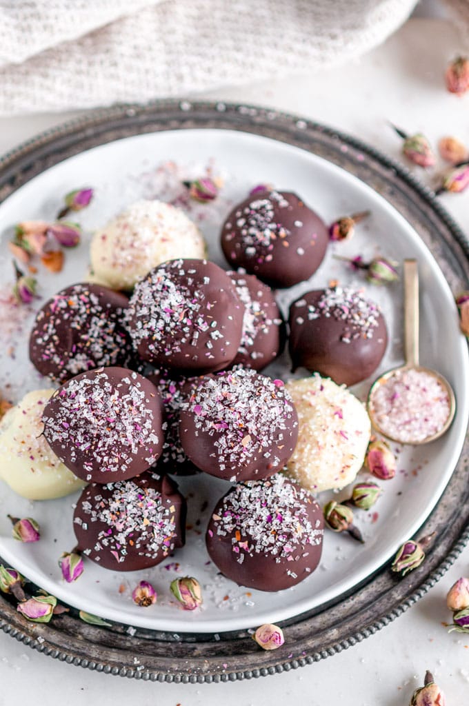 Decadent Dark Chocolate Rose Truffles sprinkled with rose buds and sanding sugars on white plate