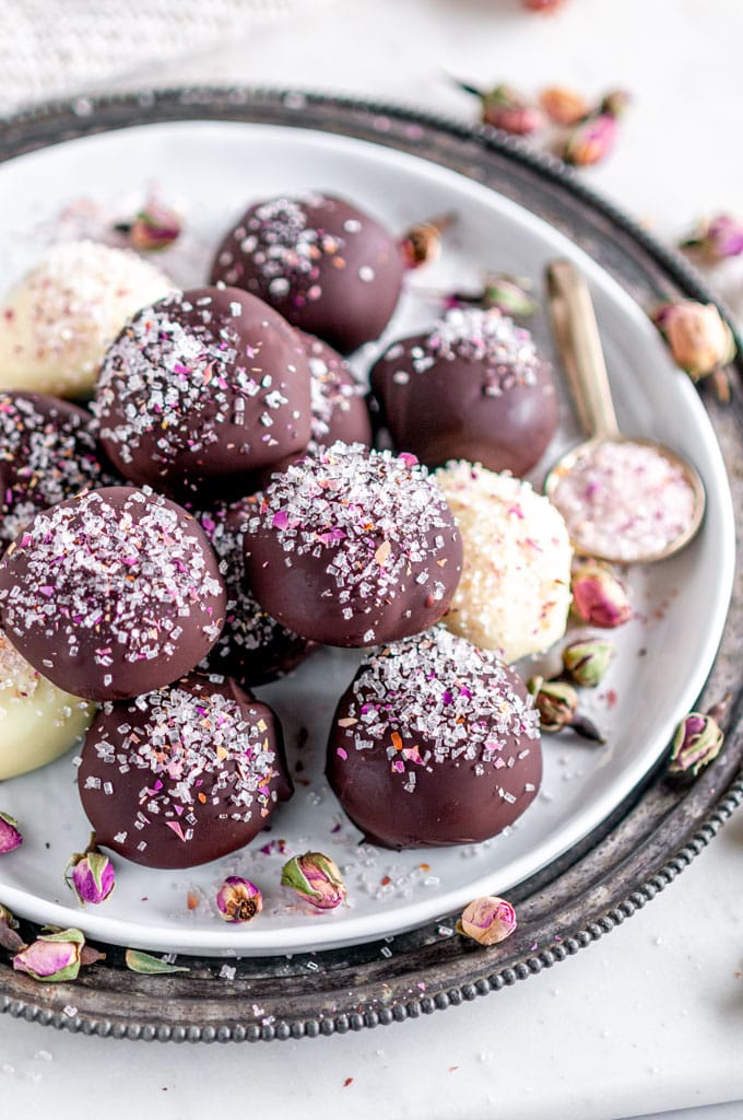 Decadent Dark Chocolate Rose Truffles sprinkled with rose buds and sanding sugars on white plate