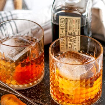 Maple Bourbon Old Fashioned Cocktail in glasses with ice on gray plate