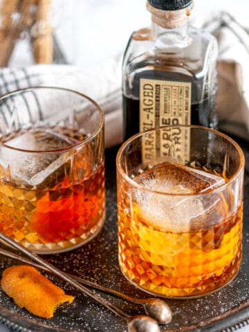 Maple Bourbon Old Fashioned Cocktail in glasses with ice on gray plate