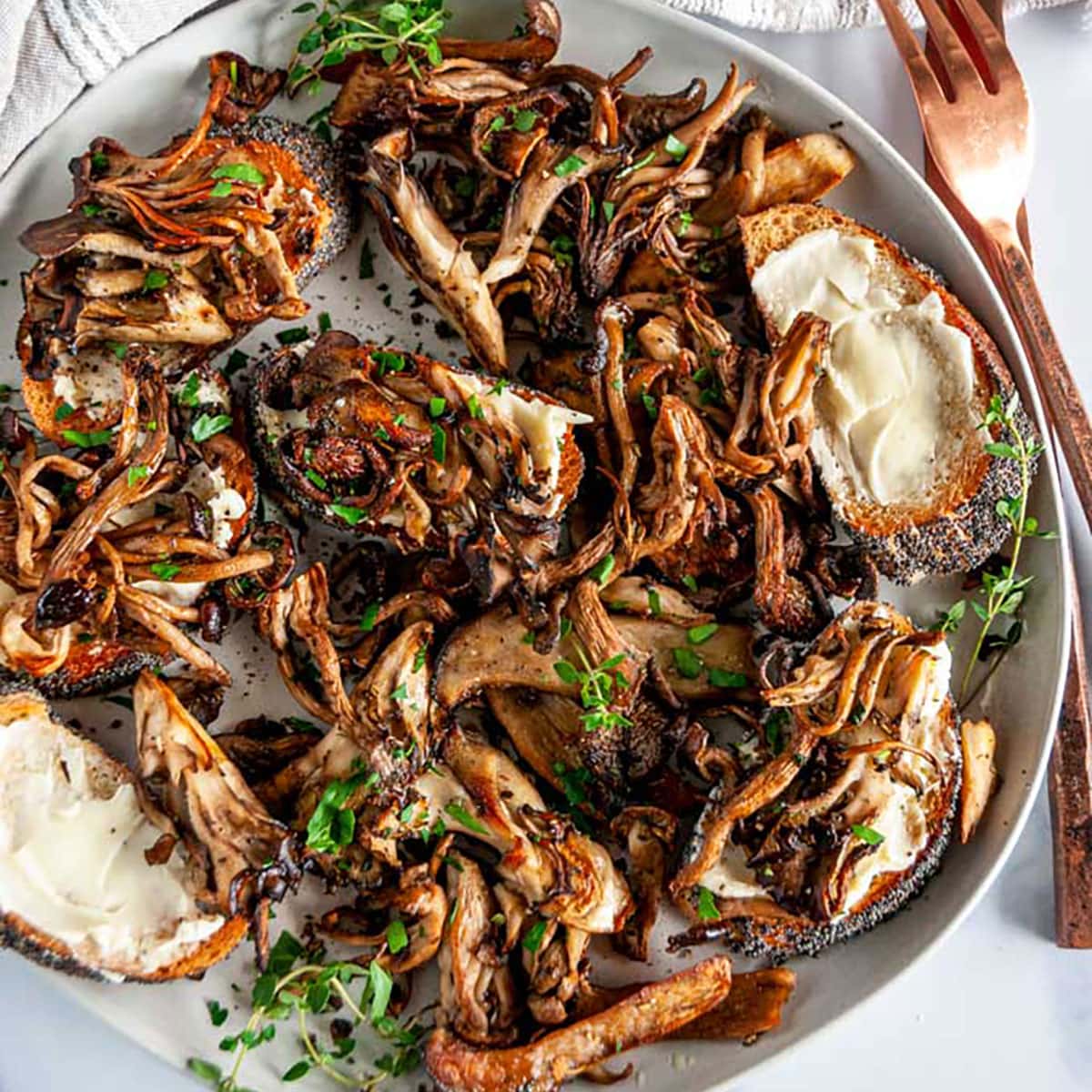 Easy Roasted Herb Mushrooms with buttered baguette slices on gray plate with copper dinner ware