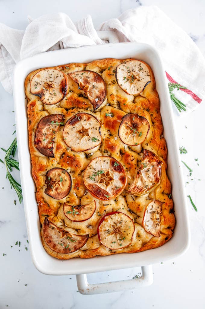Apple Rosemary Focaccia Bread in white baking dish on marble