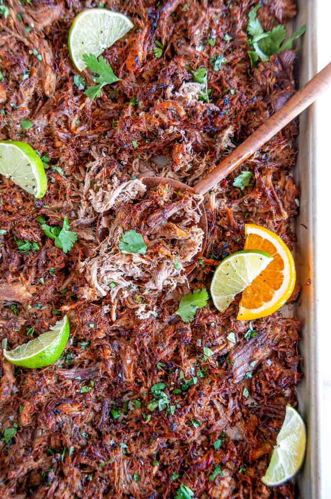 Cuban Inspired Instant Pot Pulled Pork on sheet pan with wooden spoon and citrus slices