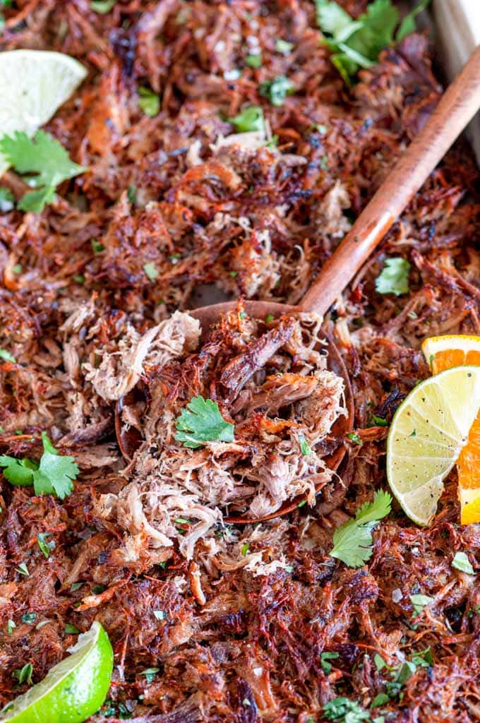 Cuban Inspired Instant Pot Pulled Pork on sheet pan with wooden spoon and citrus slices