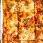 Butternut Squash Vegetable Lasagna with fresh sage in white casserole dish on marble