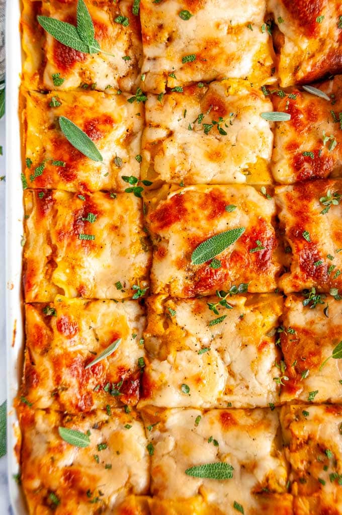 Butternut Squash Vegetable Lasagna with fresh sage in white casserole dish on marble
