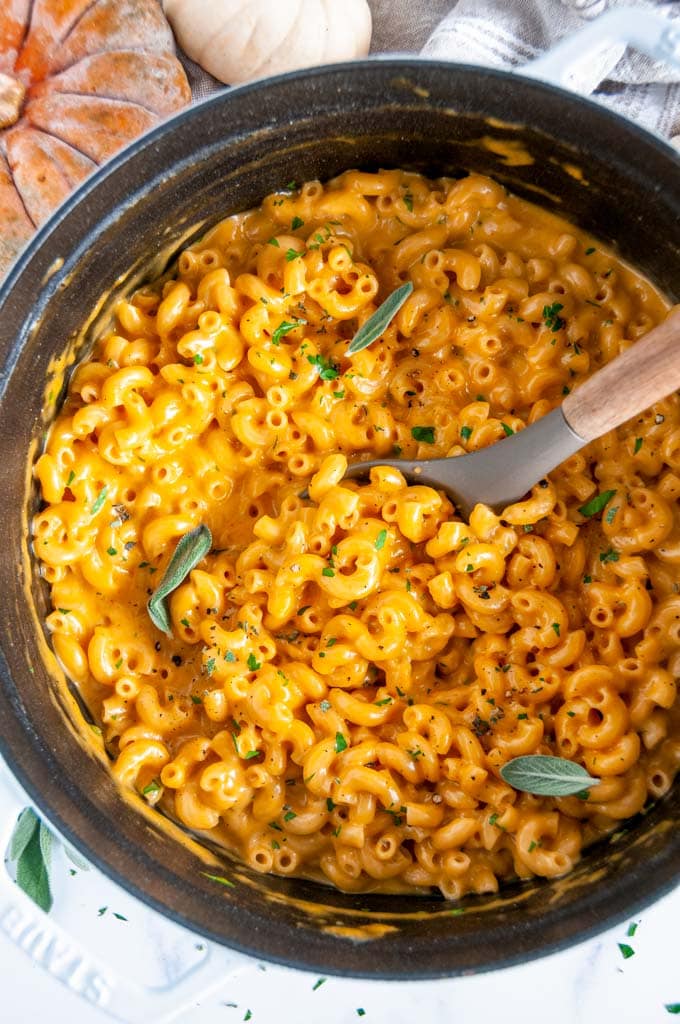 One Pot Pumpkin Mac and Cheese in white staub dutch oven with gray and wood spoon