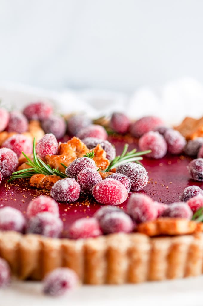 Cranberry Curd Tart with sugared cranberries and rosemary on white marble