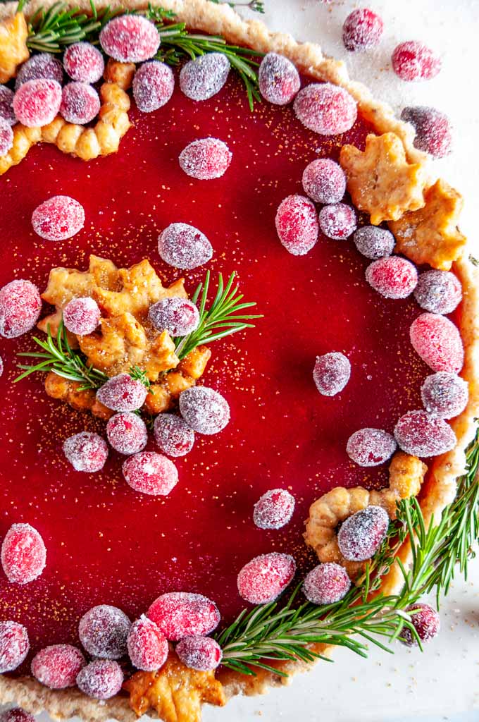 Cranberry Curd Tart with sugared cranberries and rosemary on white marble