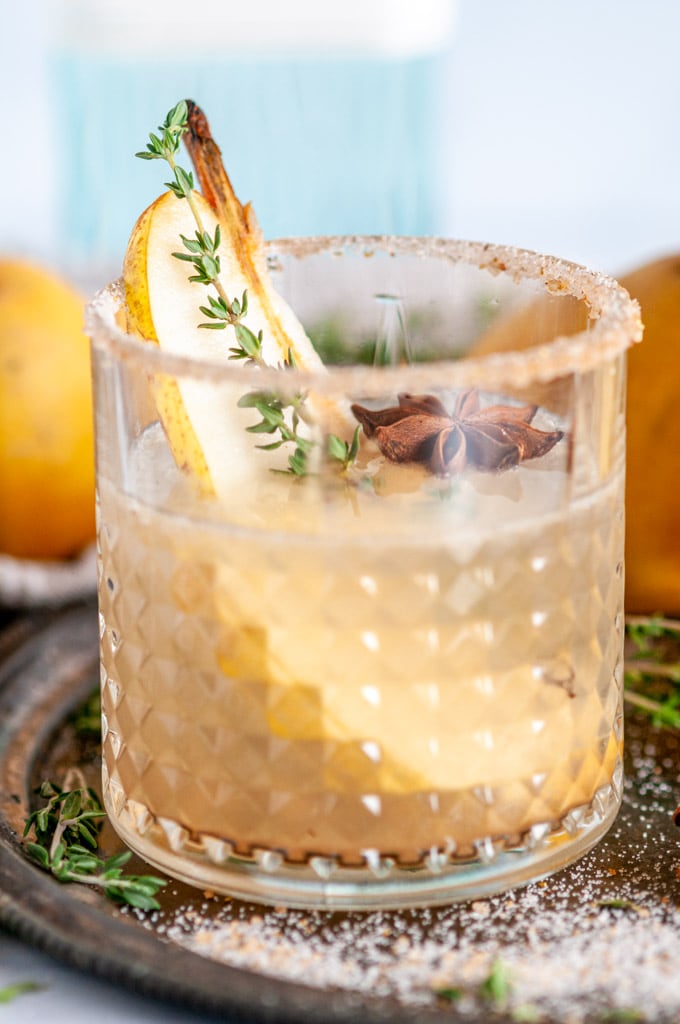 Spiced Pear Gin Fizz in cocktail glass with sanded sugar rim on gray plate
