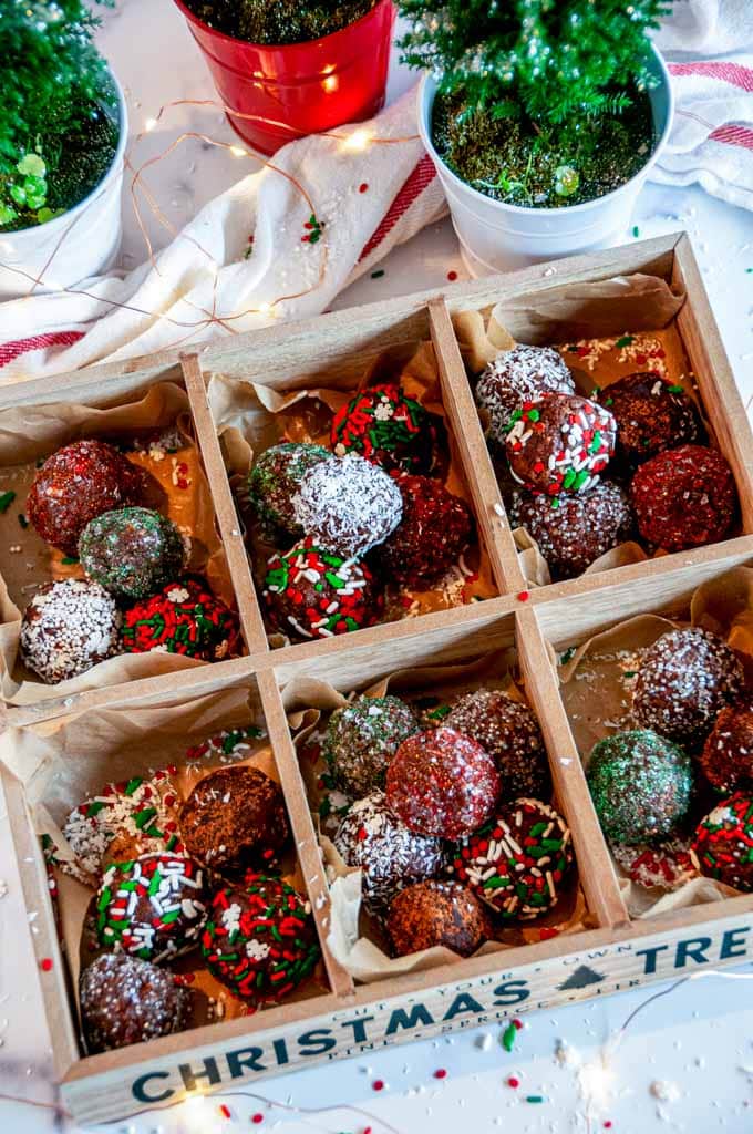 No Bake Chocolate Rum Balls in wooden cookie box with lights and potted plants