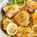 Skillet Lemon Dill Chicken Thighs in all clad pan with tea towel on white marble over head view close up