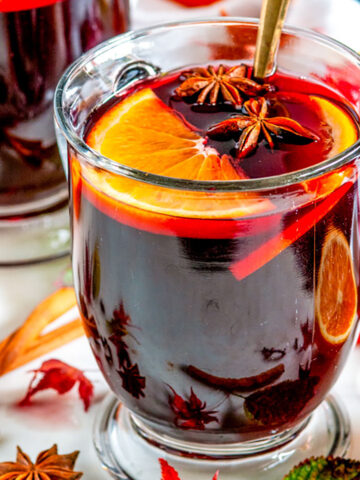 Spiced Holiday Mulled Wine in glass mugs with autumn leaves on white marble