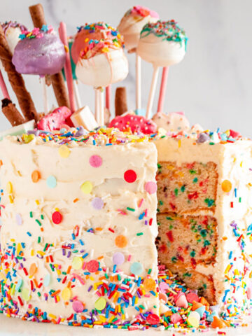 Birthday Surprise Confetti Cake with cake pops slice removed on white cake stand