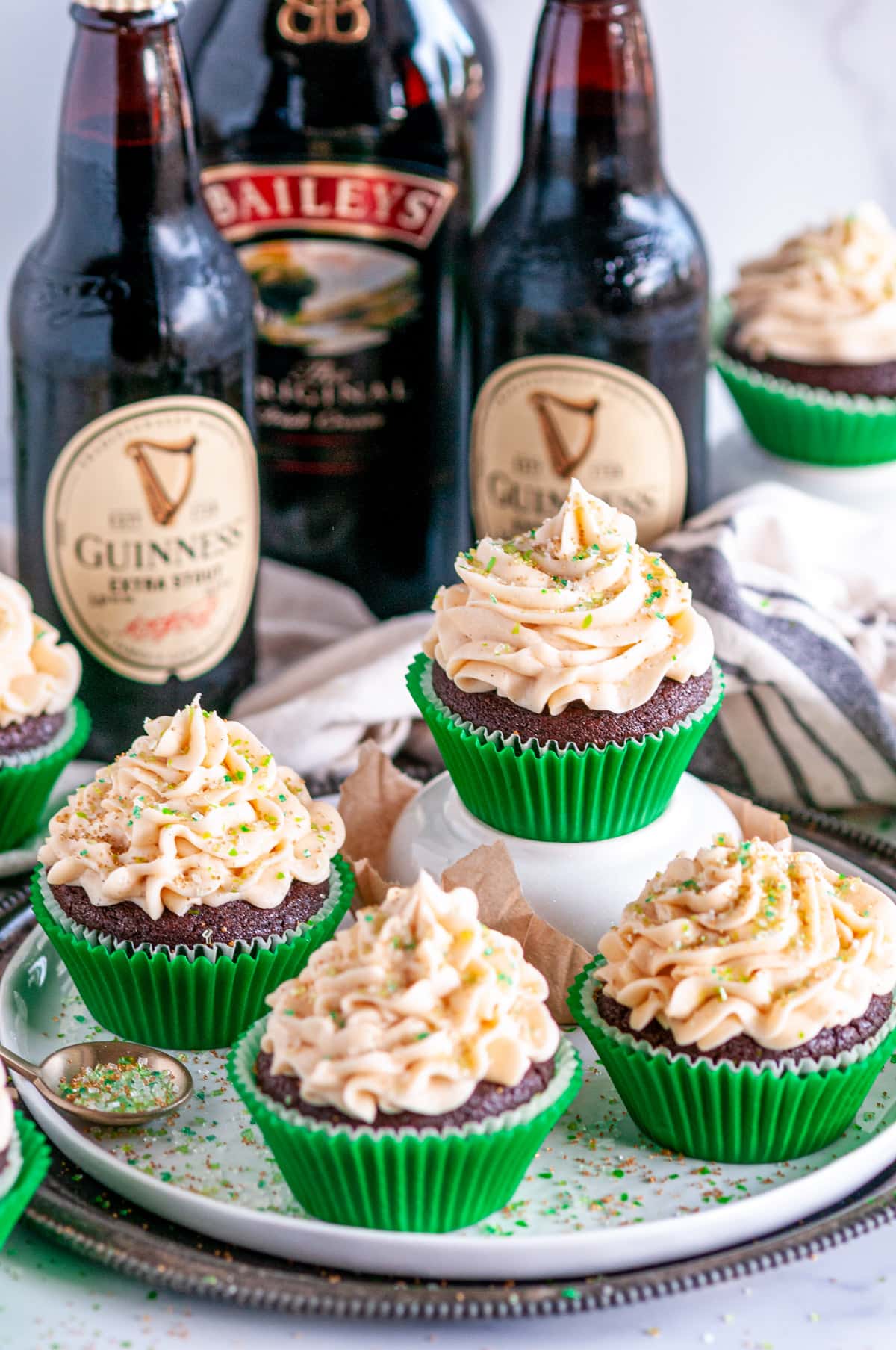 Guinness Chocolate Cupcakes with Bailey's Buttercream Frosting in green liners topped with sanding sugar on white and gray plates