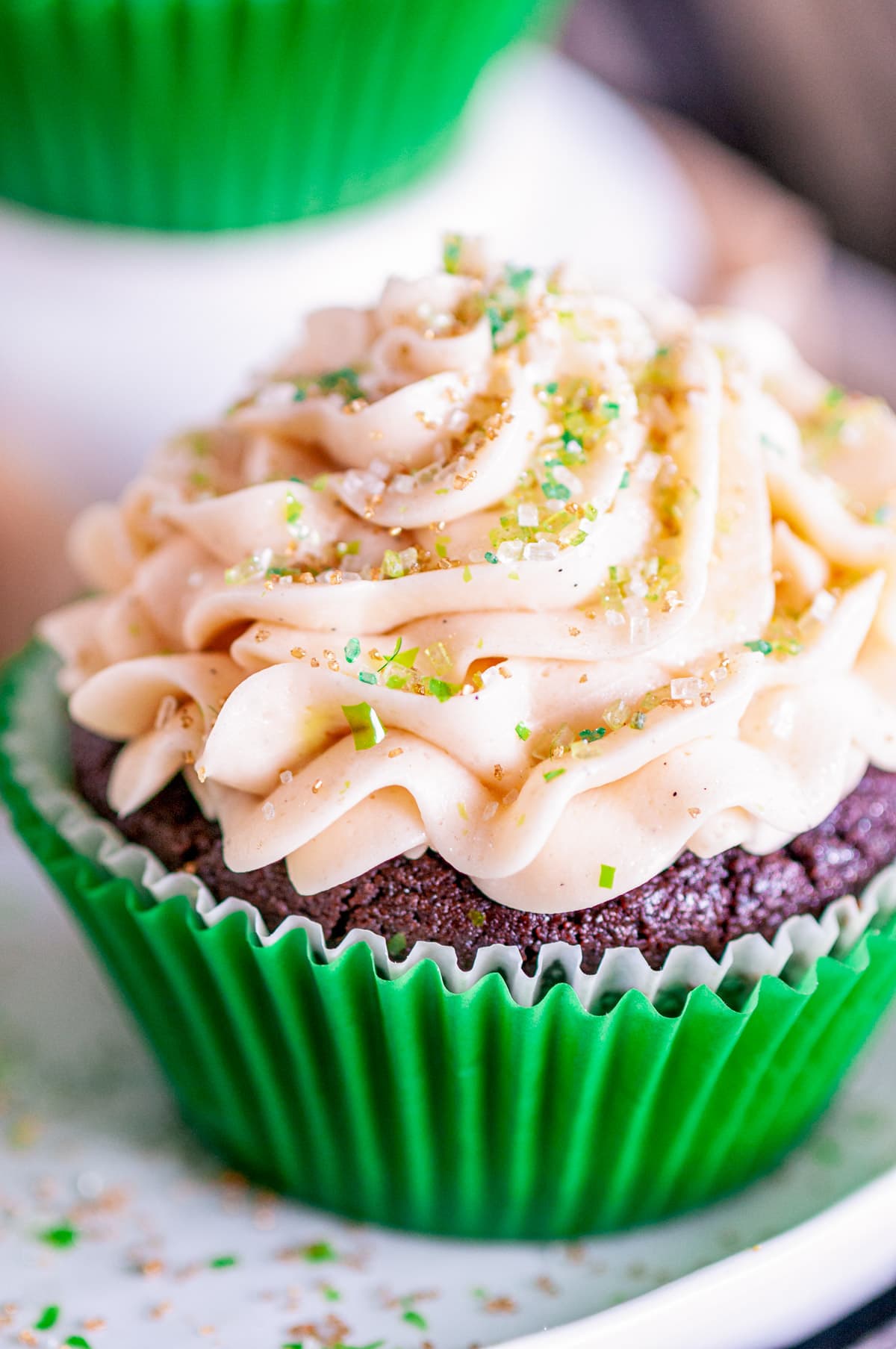 Guinness Chocolate Cupcakes with Baileys Buttercream Frosting in green liner topped with sanding sugar on white plate