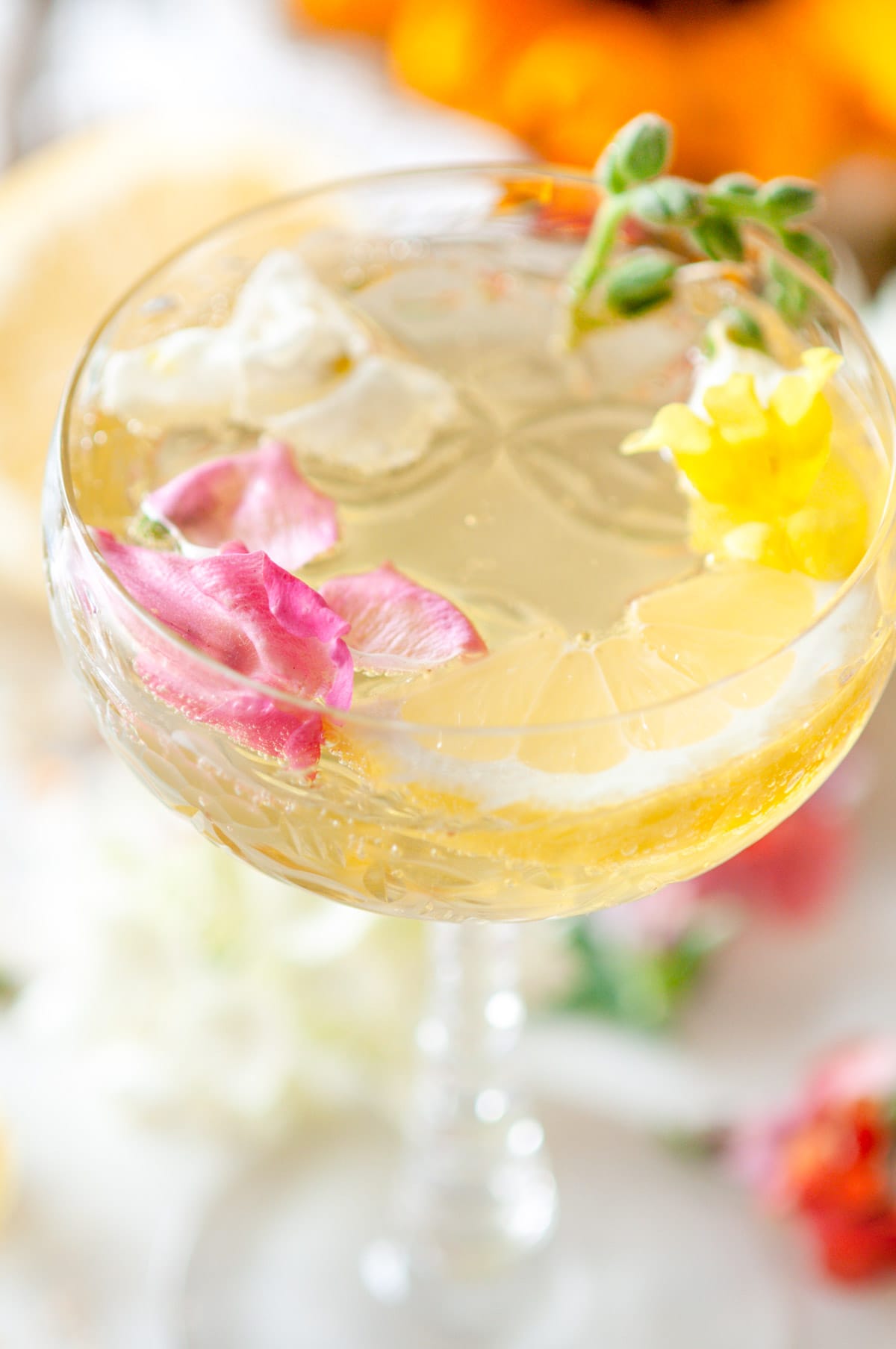 Sparkling Suze Wildflower Cocktail in crystal glasses with edible flowers on white marble