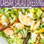 Vegetarian Caesar Salad Dressing tossed with romaine lettuce, lemons and croutons in white bowl with copper serving utensils