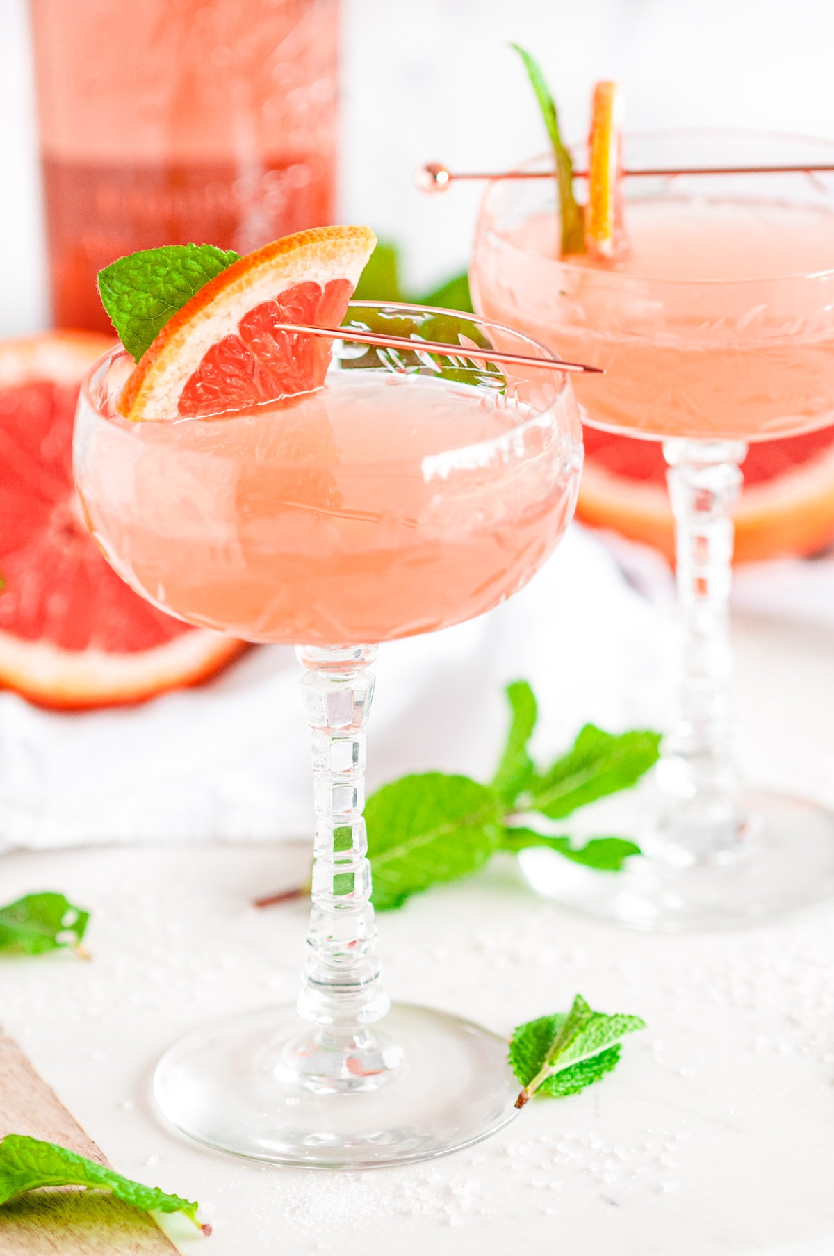 Pink Pamplemousse Gin Cocktail in crystal glasses with fresh mint on white marble
