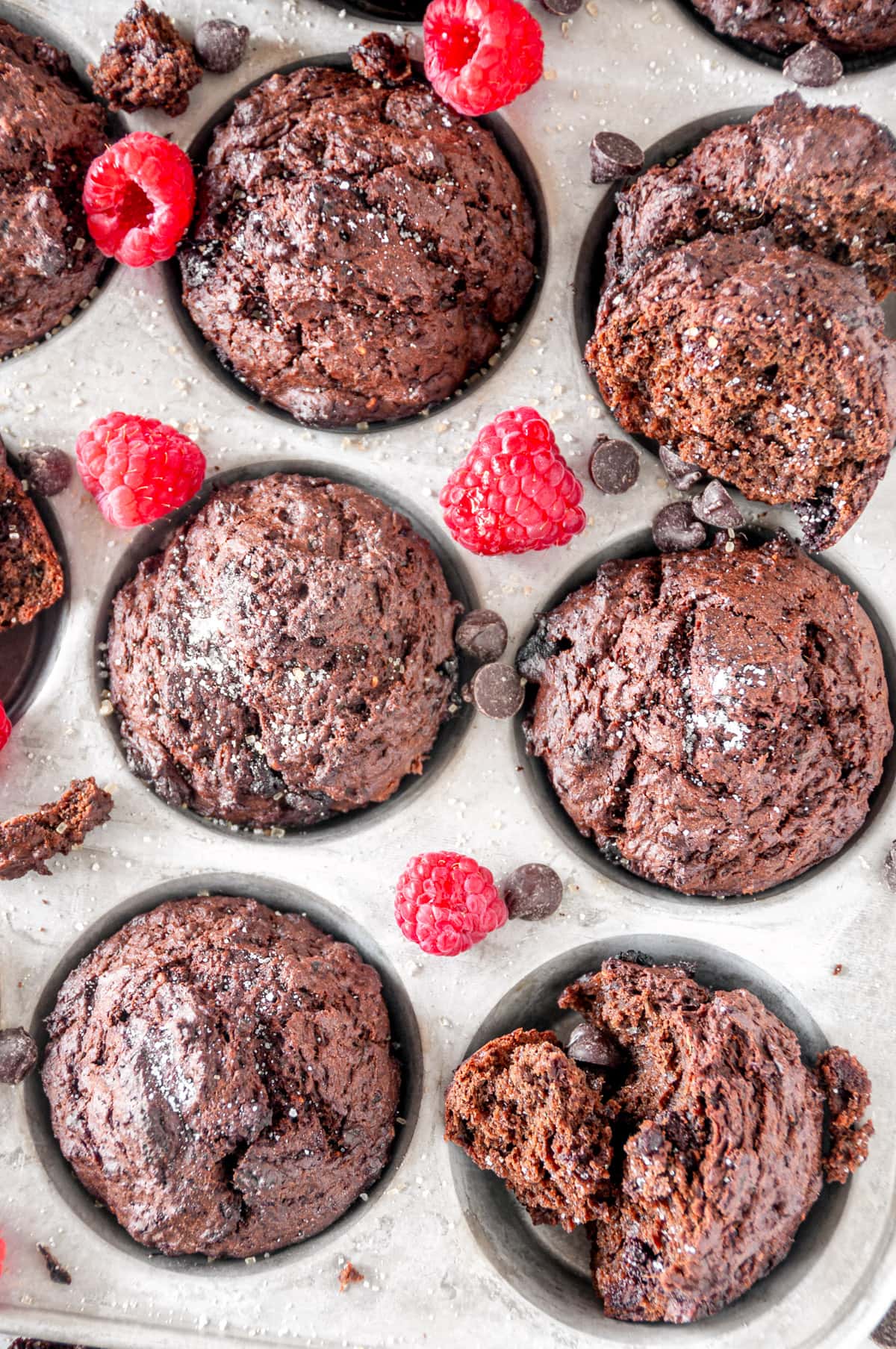 Chocolate Raspberry Veggie Muffins in silver muffin tray on white marble with chocolate chips close up