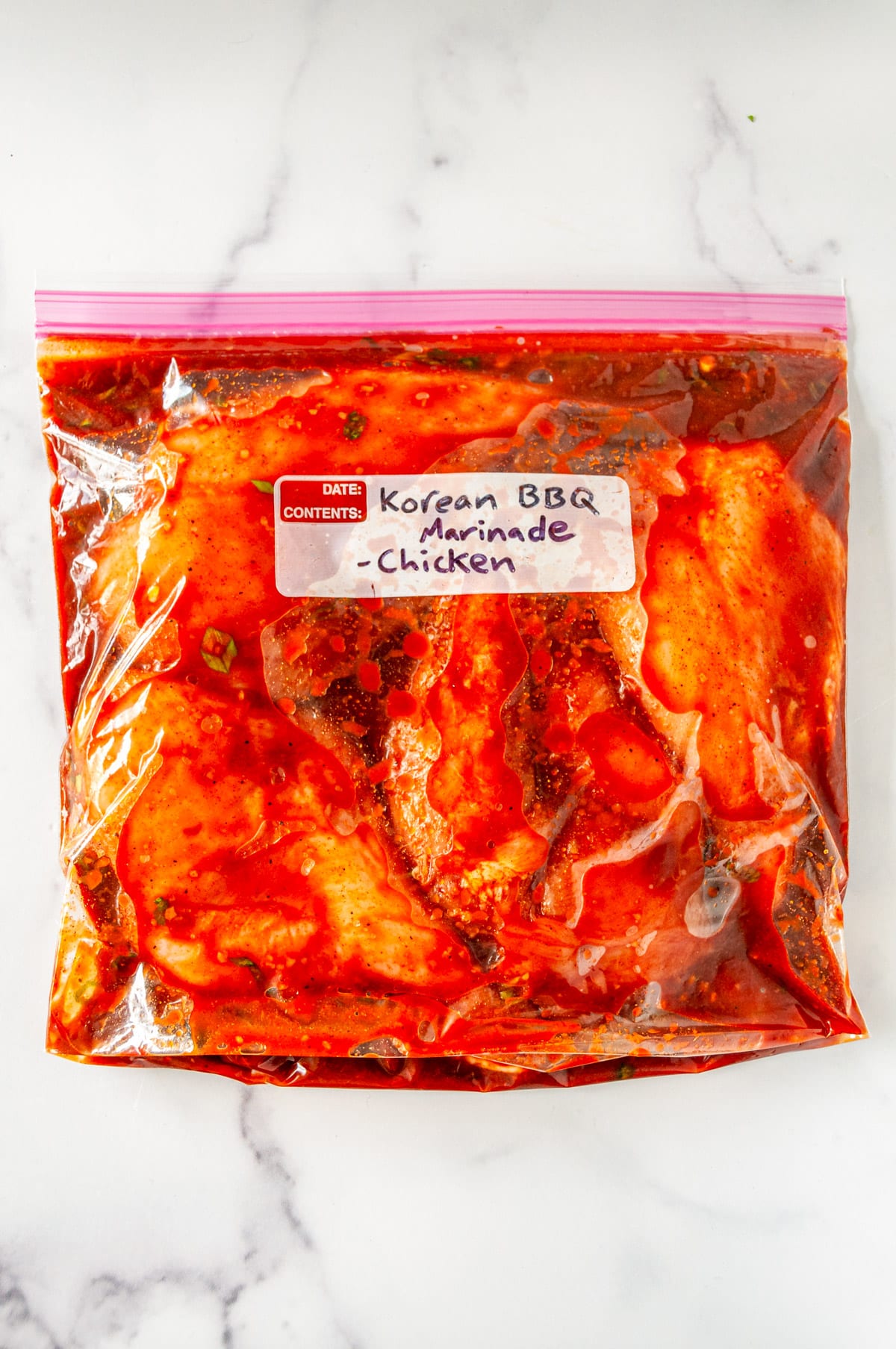 Korean BBQ Marinade Recipe raw chicken dressed in plastic bag on white marble