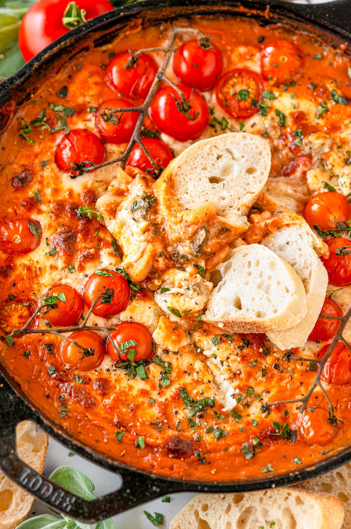 Cheesy White Bean Skillet Bake with sliced baguette and cherry tomatoes in lodge cast iron skillet on white marble
