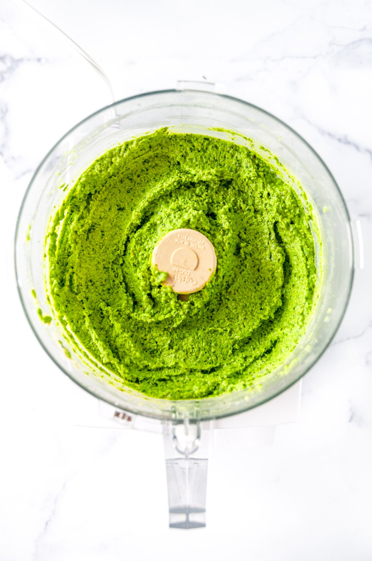 Mint Pea Dip blended in food processor on white marble overhead view