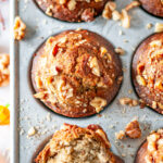 Maple banana muffins in gray metal muffin pan with walnuts and leaves on white marble