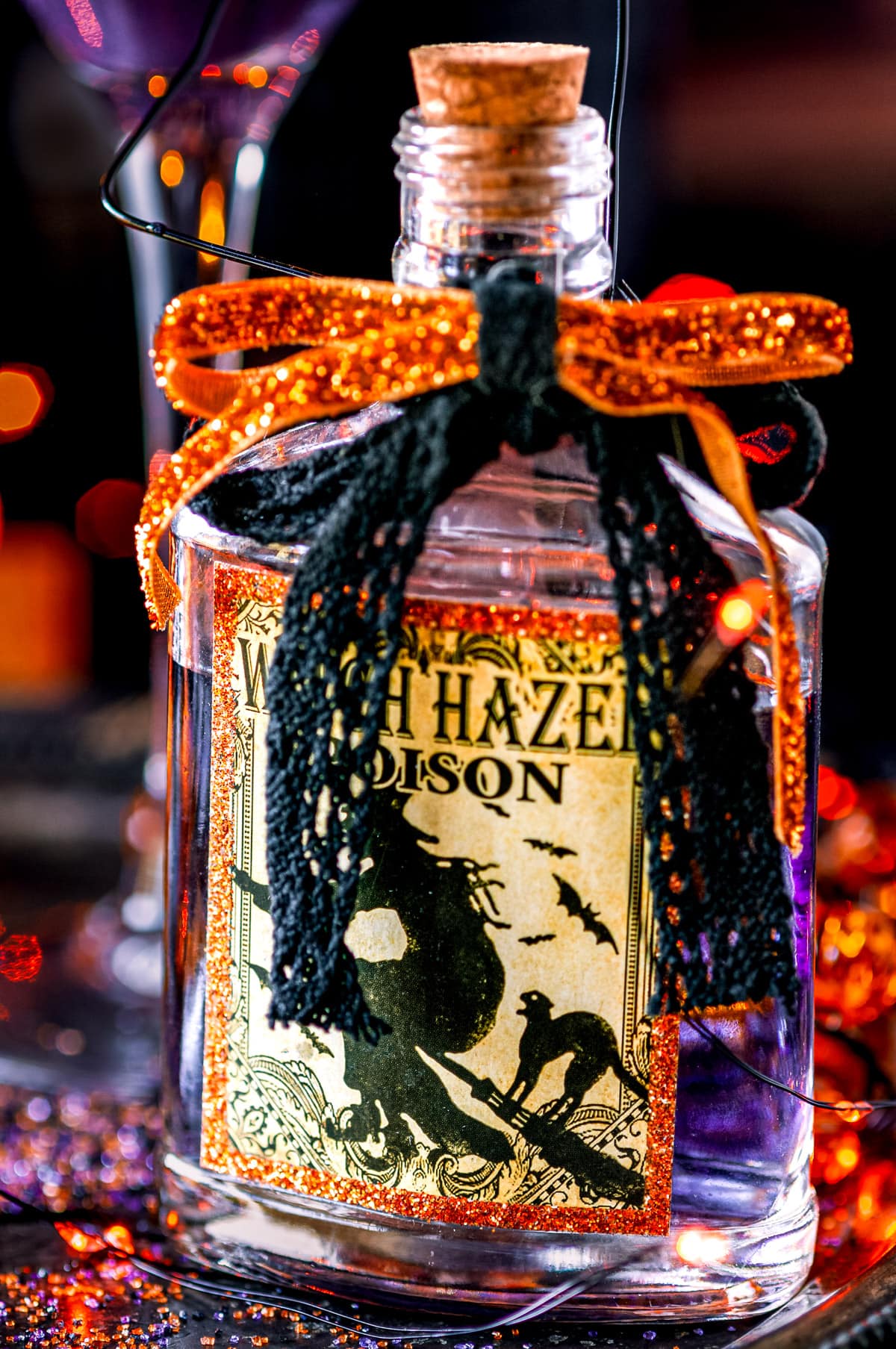 Halloween Hocus Pocus Cocktail in witch hazel poison bottle with candles in background