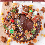 Gingerbread Chocolate Tart topped with gingerbread cookies, festive sprinkles, and candied ginger on white marble