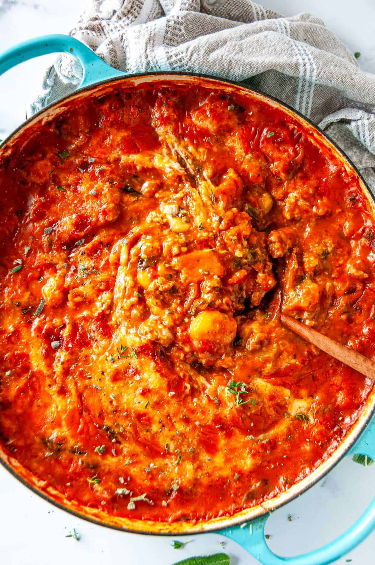 Overhead view of one pot autumn gnocchi being stirred, showing the creamy tomato-squash sauce, tender gnocchi, and browned sausage