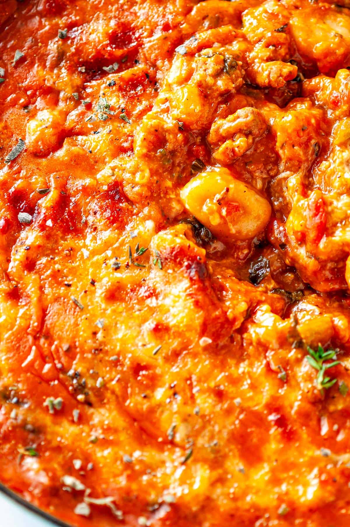 Close-up of saucy one pot autumn gnocchi with chunks of butternut squash and Italian sausage in a rich, cheesy tomato sauce.