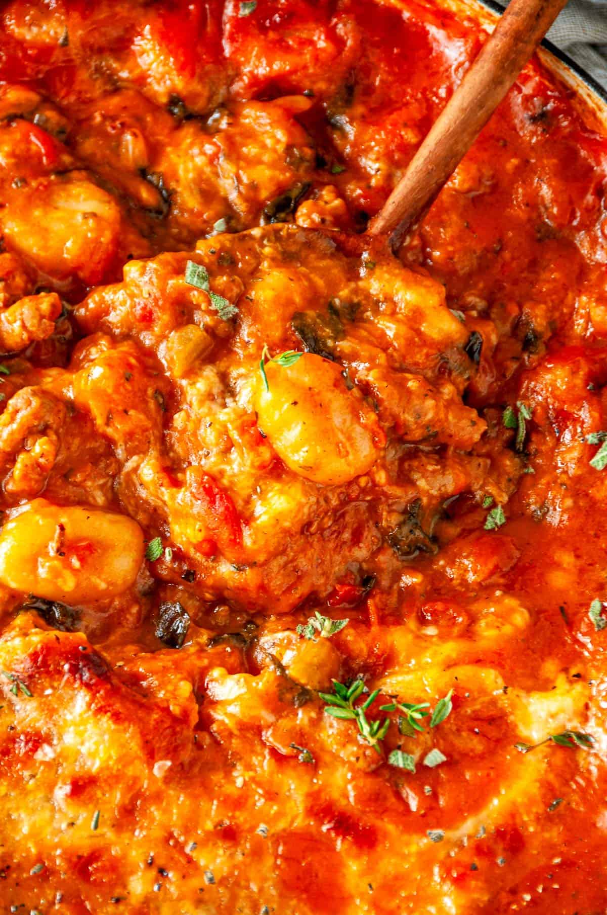 Extreme close-up of one pot autumn gnocchi, highlighting the melty cheese, tender gnocchi, and savory sausage in a creamy tomato-sage sauce.